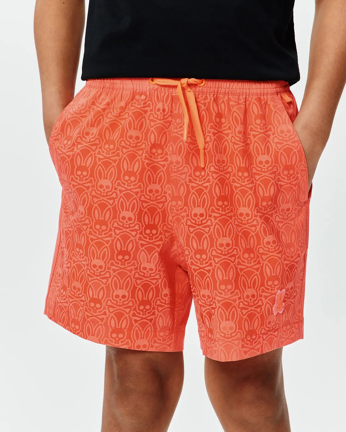 Coral orange Kids Samos Hydrochromic Printed Swim Trunk, relaxed fit, quick-dry, all-over tonal bunny skull and crossbones pattern, orange drawstring, small pink embroidered bunny skull on lower left leg.