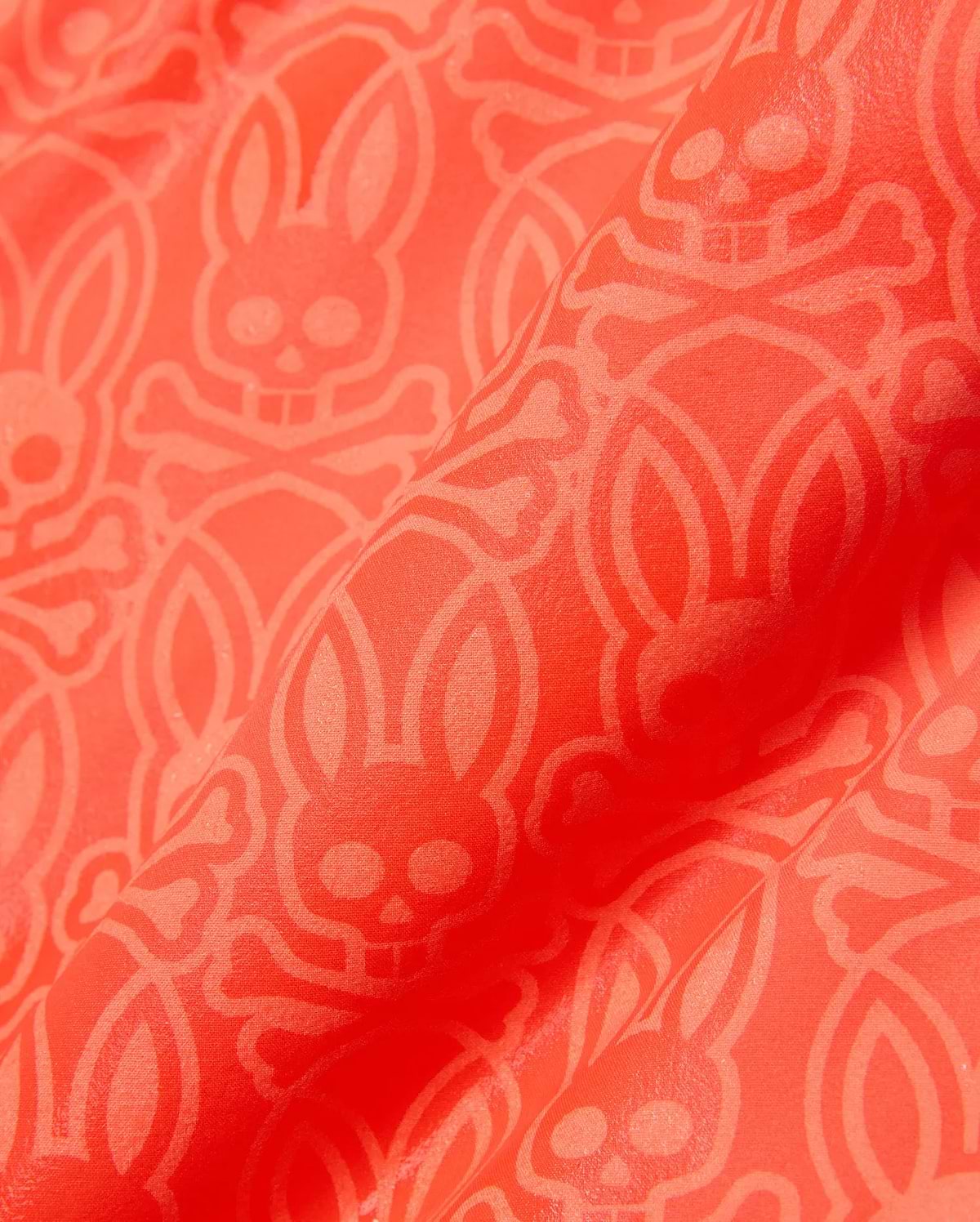 Kids Samos Hydrochromic Printed Swim Trunk in vibrant coral orange, featuring an all-over tone-on-tone geometric pattern with the iconic Psycho Bunny skull and crossbones logo.