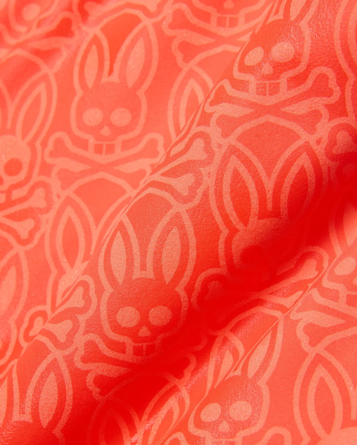 Kids Samos Hydrochromic Printed Swim Trunk in vibrant coral orange, featuring an all-over tone-on-tone geometric pattern with the iconic Psycho Bunny skull and crossbones logo.