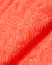 Kids Samos Hydrochromic Printed Swim Trunk in vibrant coral orange, featuring an all-over tone-on-tone geometric pattern with the iconic Psycho Bunny skull and crossbones logo.