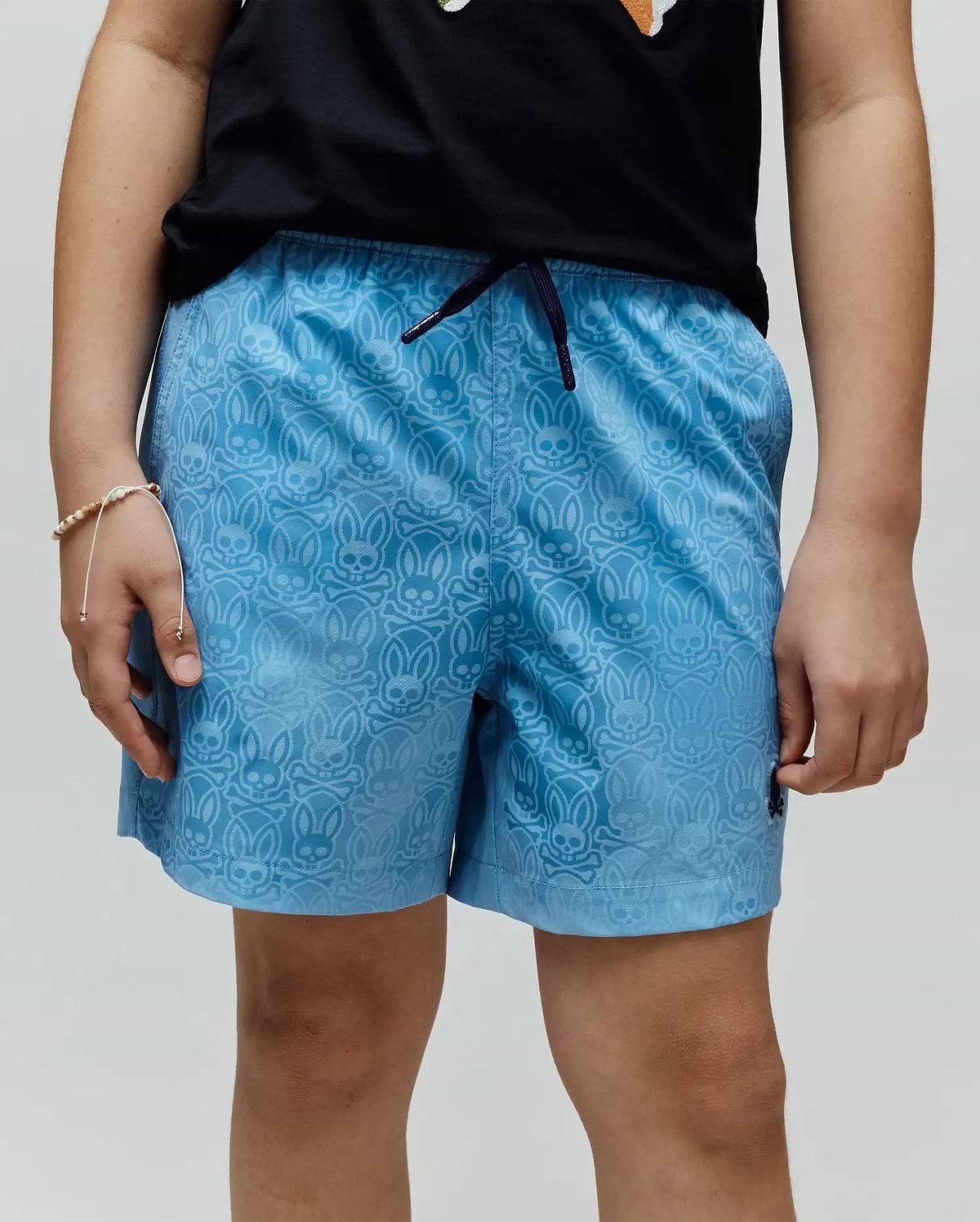 Kids Samos Hydrochromic Printed Swim Trunk, light blue with an all-over tonal Psycho Bunny skull and crossbones pattern, dark blue drawstring, and small embroidered logo on the left leg.