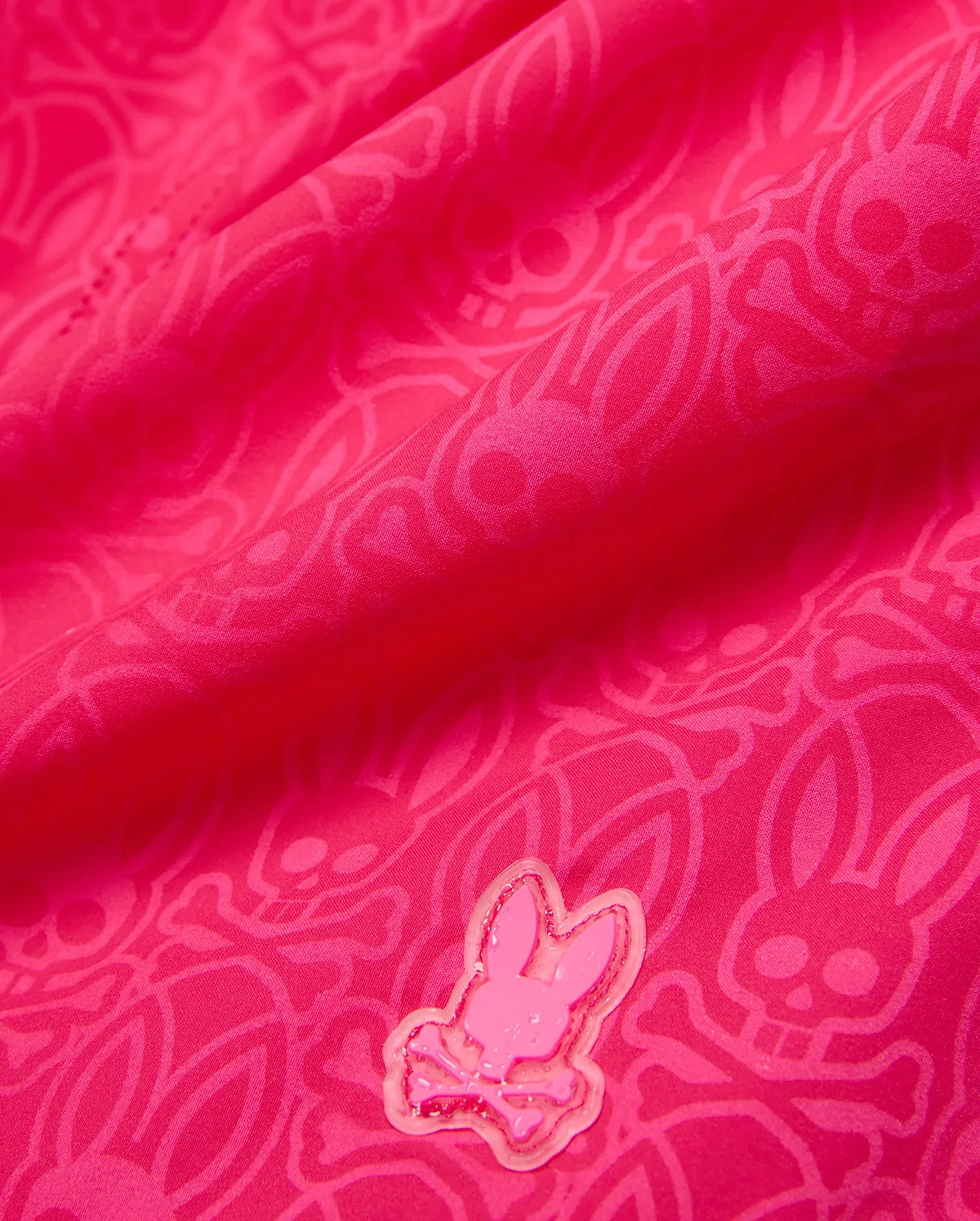 Kids Samos Hydrochromic Printed Swim Trunk in vibrant fuchsia, featuring a subtle tonal hydrochromic Psycho Bunny skull and crossbones pattern, with a raised, glossy pink Psycho Bunny logo emblem.