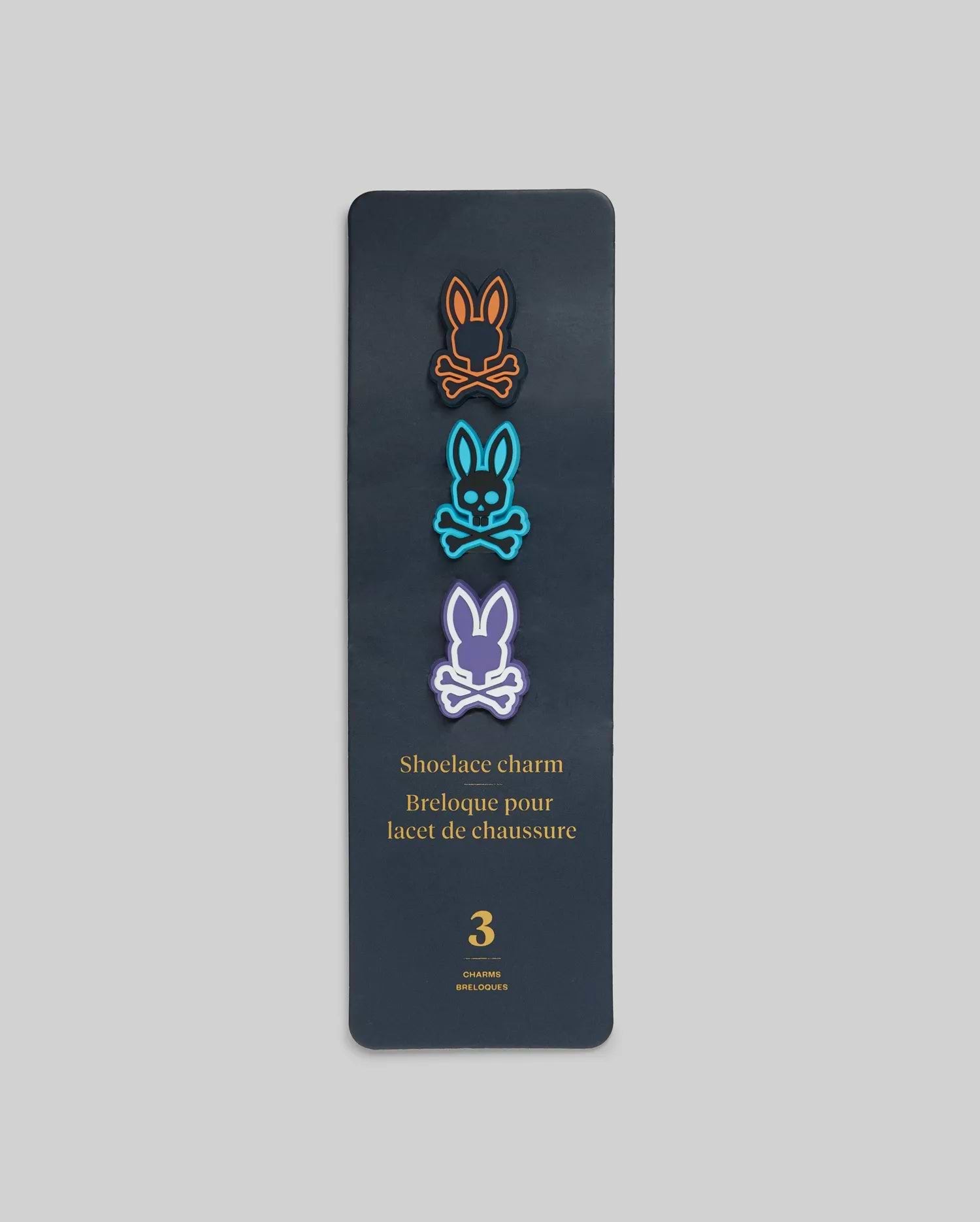 Psycho Bunny Shoe Lace Charms set featuring three iconic bunny skull logos in vibrant orange, blue, and purple, outlined in black, on a dark grey card.