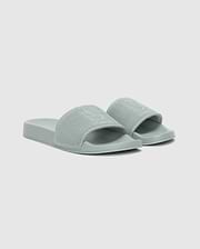 The Psycho Bunny MENS KNIT SLIDES - B6A474F200 are light green sandals with textured wide straps and an ergonomically molded footbed for comfort, shown on a plain white background.