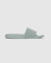 The Psycho Bunny MENS KNIT SLIDES - B6A474F200 feature a light green knit upper, textured wide strap, flat sole, and ergonomically molded footbed, shown in side profile against a plain light background.