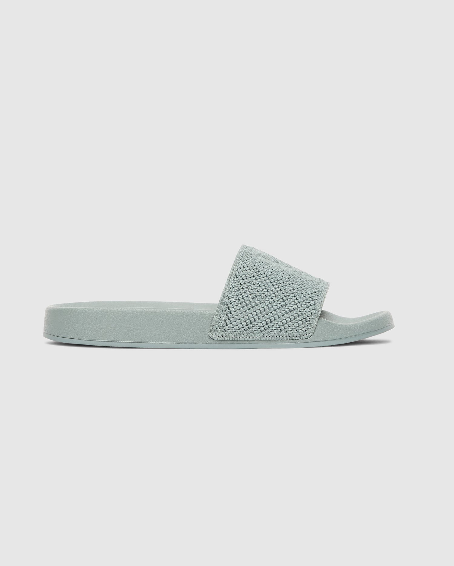 The Psycho Bunny MENS KNIT SLIDES - B6A474F200 feature a light green knit upper, textured wide strap, flat sole, and ergonomically molded footbed, shown in side profile against a plain light background.