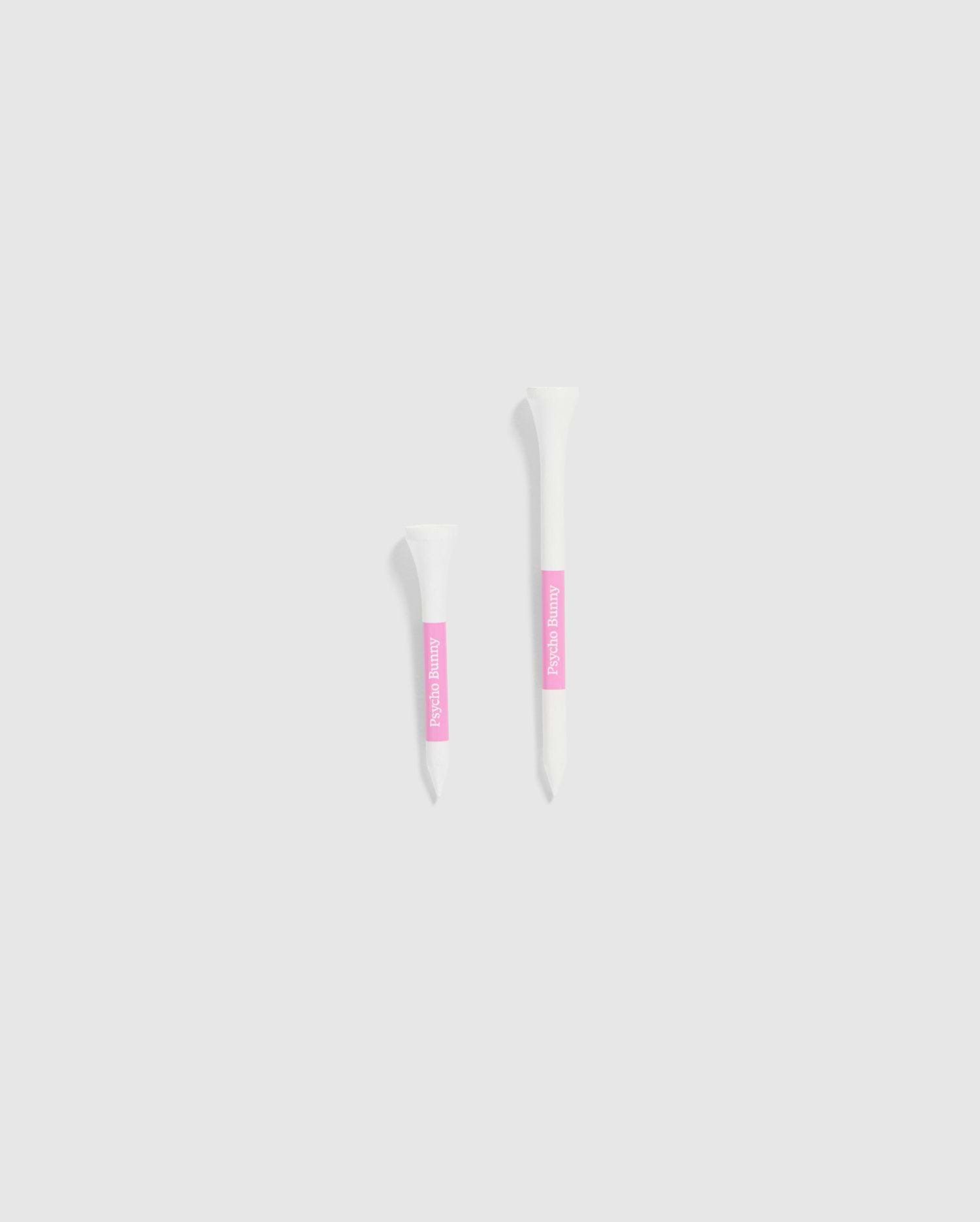 The image features two white tubes set against a light gray background, each with a pink label. The smaller tube is positioned on the left and is decorated with Psycho Bunny's 75 PACK GOLF TEES - B6A659C200, accented by bunny-themed designs. The larger tube is on the right, ideal for those looking for whimsical golf accessories from the Psycho Bunny brand.