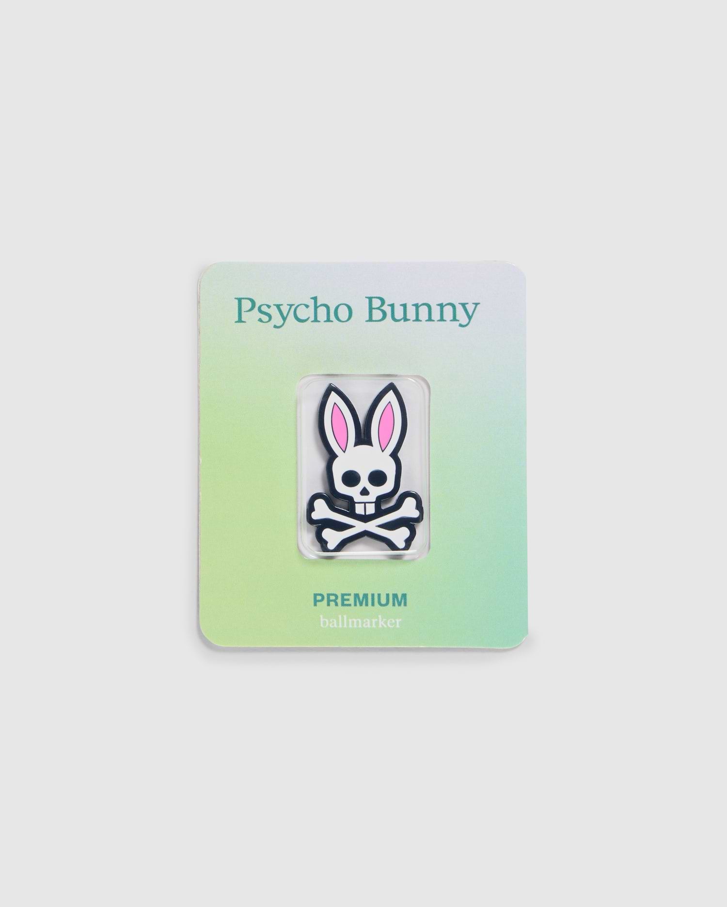 Explore the Psycho Bunny golfers collection with this premium ball marker featuring a white skull with pink bunny ears. Attached to a gradient card transitioning from light green to light blue, it showcases "Psycho Bunny" at the top and "PREMIUM BALL MARKER - B6A698C200" at the bottom.