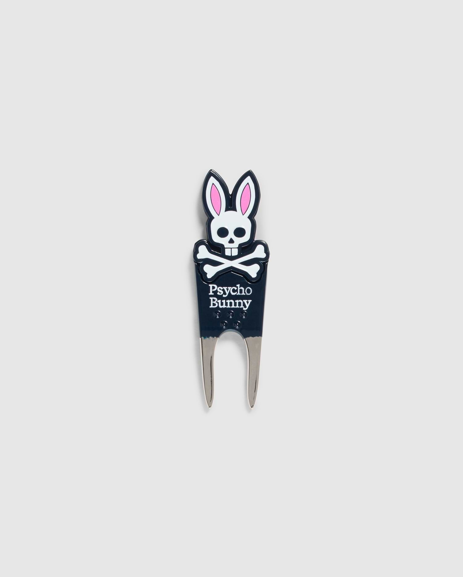Image of a DIVOT TOOL - B6A699C200 from Psycho Bunny with a design featuring a skull with bunny ears and the text "Psycho Bunny" underneath. The tool has two prongs at the bottom, and the skull and ears are in black, white, and pink. A perfect addition to golf gifts, this tool also comes with a magnetic ball marker. The background is plain gray.