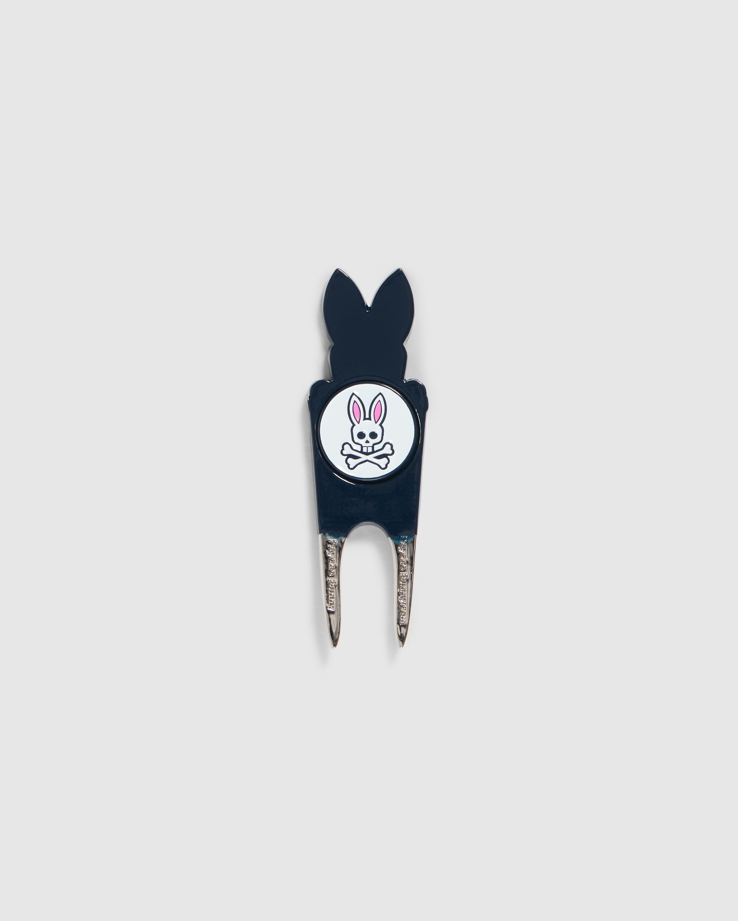 A Psycho Bunny DIVOT TOOL - B6A699C200 featuring a black handle with a white circular logo. The logo shows an illustration of a bunny head with crossed bones underneath. The two prongs of the tool are metal, and it includes a magnetic ball marker. Ideal for those seeking unique golf gifts.