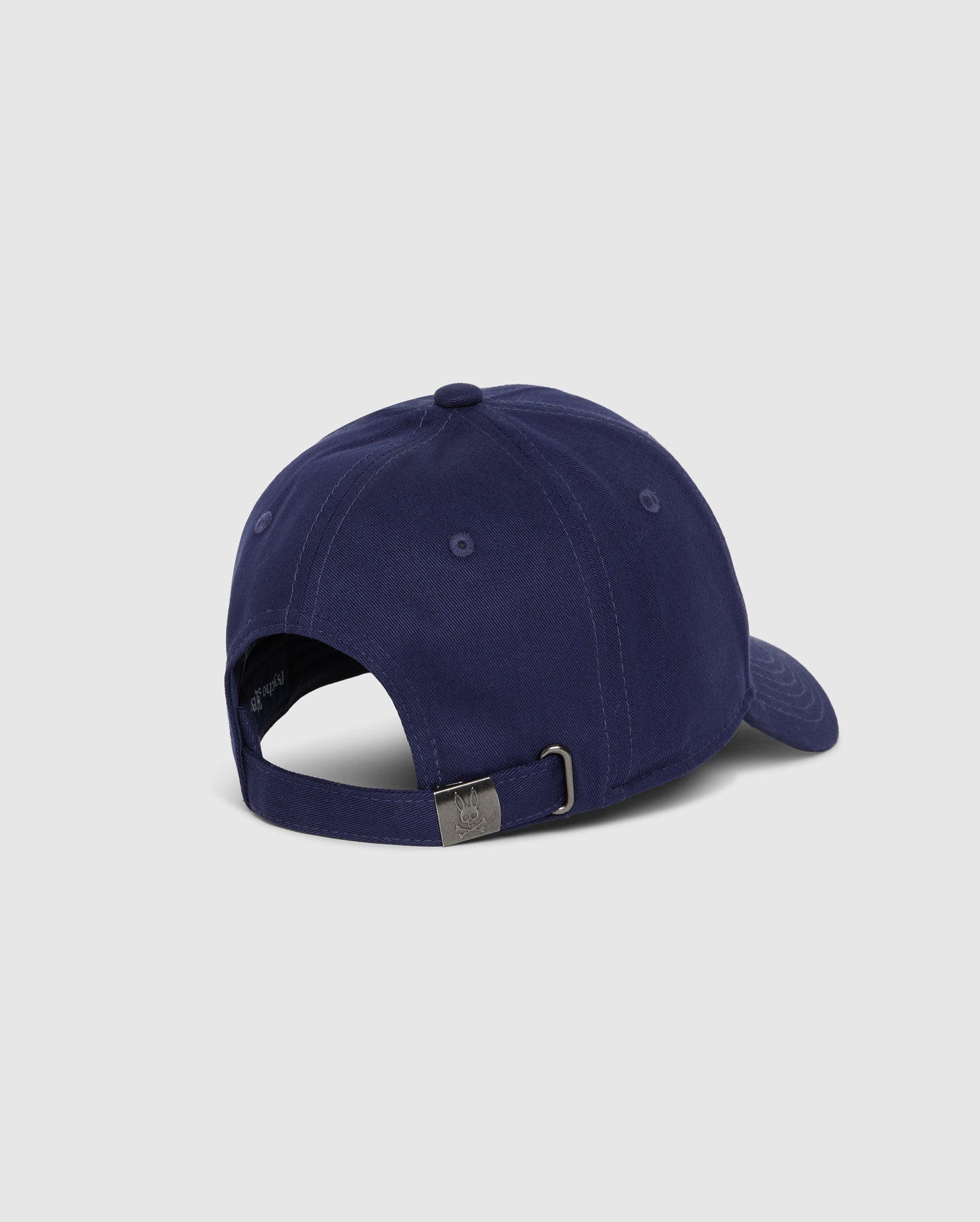 A rear view of the Psycho Bunny MENS CLASSIC BASEBALL CAP - B6A816A1HT in navy blue, featuring an adjustable strap with a metal buckle. Made from 100% cotton, this cap is set against a plain, light grey background.