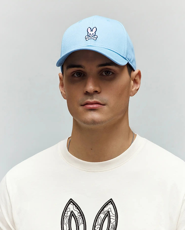 Mens Classic Baseball Cap in a vibrant light blue, crafted from smooth cotton twill, featuring a detailed embroidered white and navy Psycho Bunny skull logo prominently centered on the front panel.