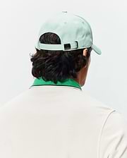 Mint Green Mens Classic Baseball Cap with a Psycho Bunny skull logo on the metal buckle, paired with a cream pique polo shirt featuring a green ribbed collar and navy stripe.