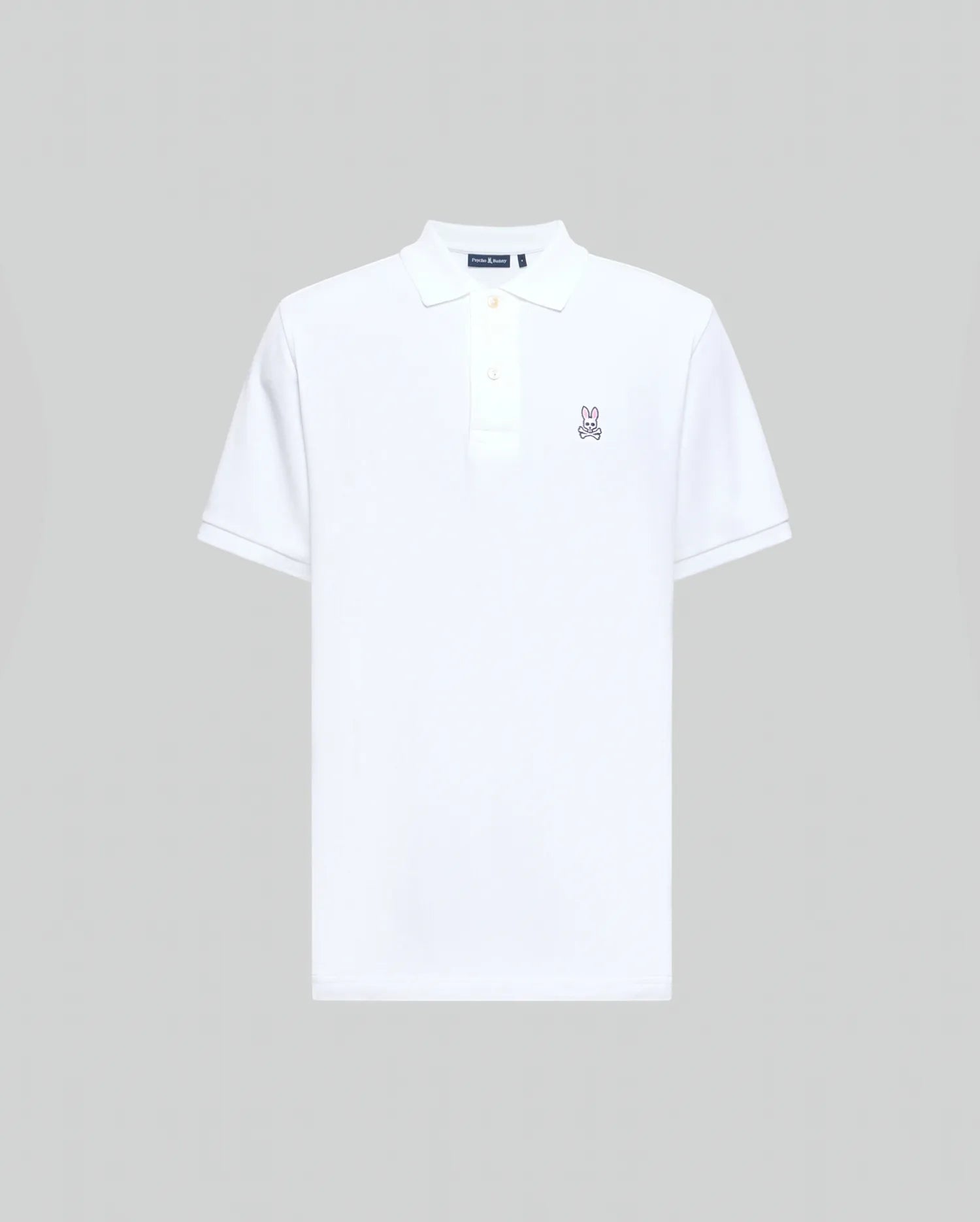 Mens Classic Pique Polo Shirt in crisp white, classic fit, pique knit, with a two-button placket, ribbed collar and cuffs, and a small embroidered pink/purple Psycho Bunny skull logo on the left chest.