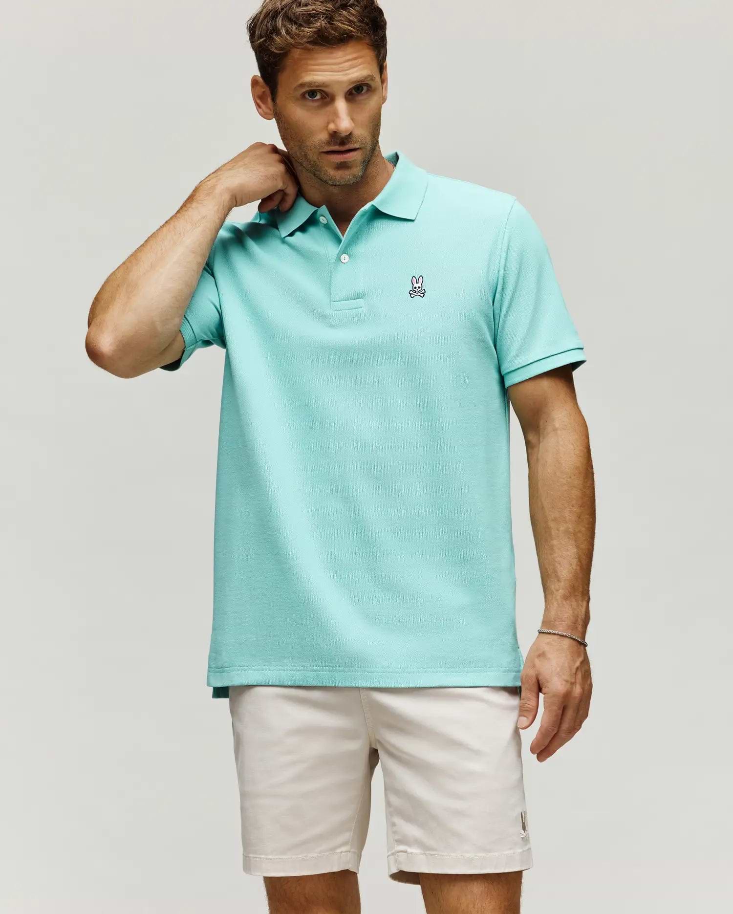 Mens Classic Pique Polo in aqua, featuring a classic fit, pique knit texture, two white buttons, and a small embroidered black, white, and pink Psycho Bunny skull logo on the left chest.