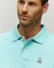Mens Classic Pique Polo in aqua, featuring a classic fit, textured pique knit fabric, two-button placket, and a small embroidered pink and white Psycho Bunny skull logo on the left chest.