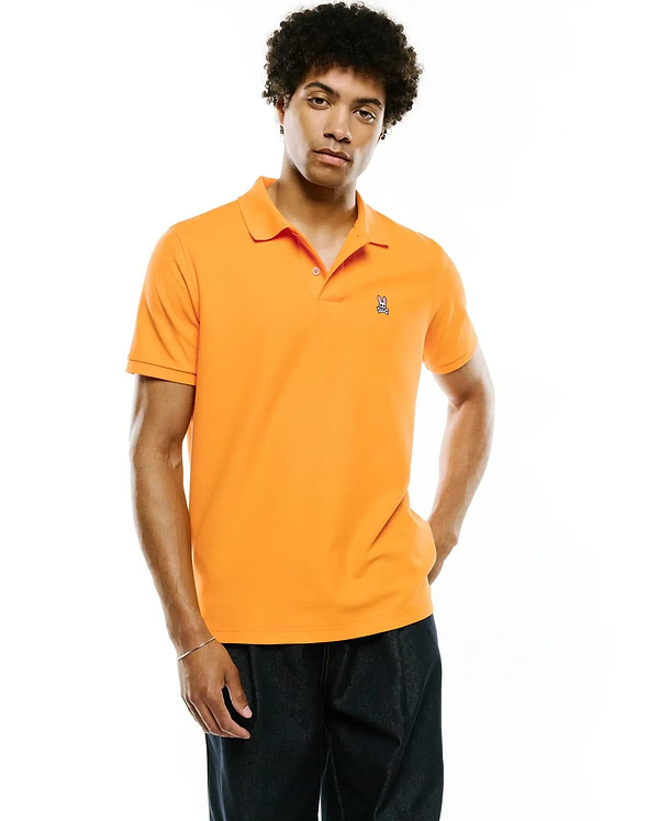 Mens Classic Pique Polo in vibrant orange pique knit, featuring a classic fit and a small, embroidered white and pink Psycho Bunny skull logo on the left chest.