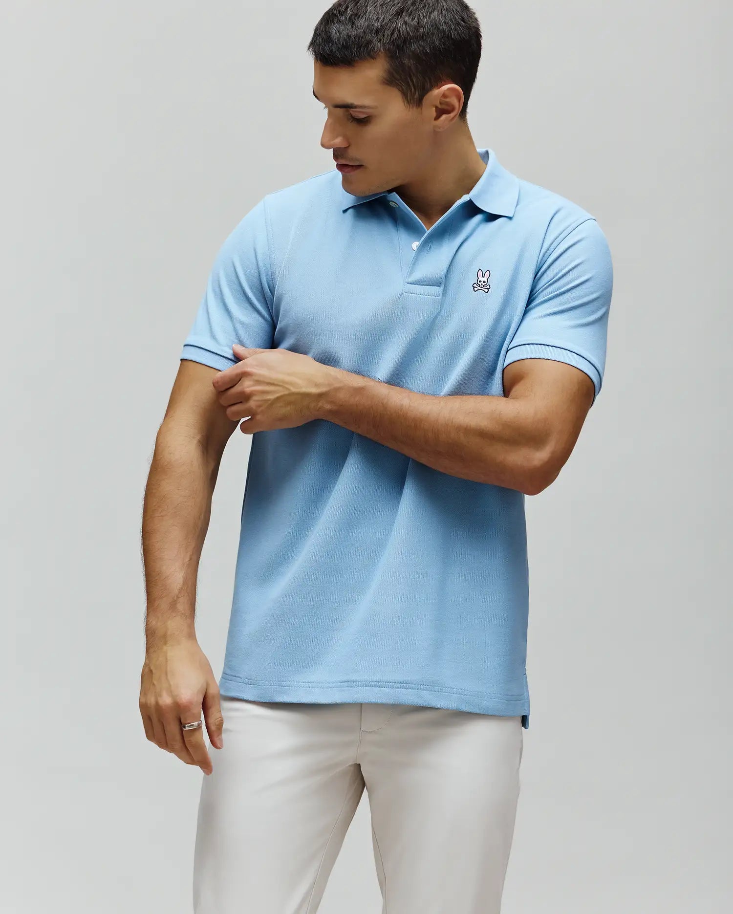 Mens Classic Pique Polo, light blue classic fit pique knit with a two-button placket and a small embroidered Psycho Bunny skull logo on the left chest.