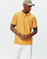 Golden orange pique knit Mens Classic Pique Polo, featuring a classic fit, two-button placket, and a small embroidered white and black Psycho Bunny skull logo on the left chest.