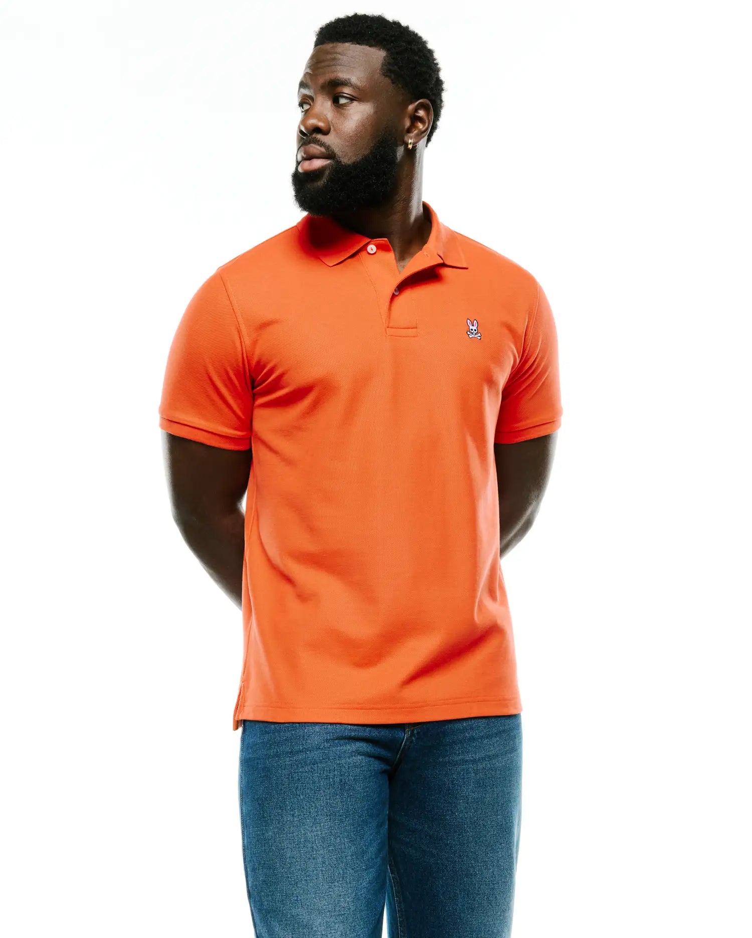 Men's Classic Pima Pique Polo in vibrant orange, featuring a classic fit, textured pique fabric, two-button placket, and a small embroidered Psycho Bunny skull logo on the left chest. (1)