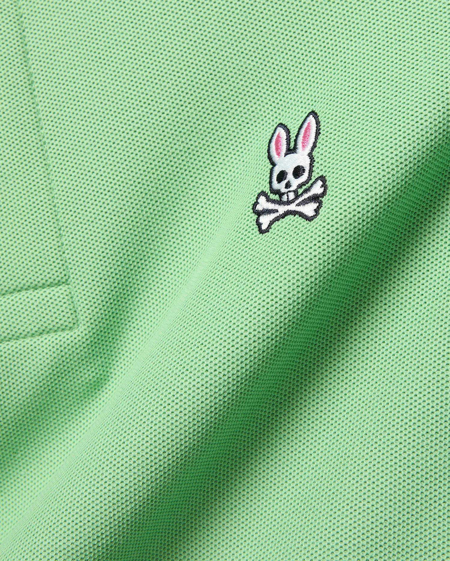 Mens Classic Pique Polo in vibrant light green, showcasing a detailed embroidered white, black, and pink Psycho Bunny skull logo on the left chest. (7)