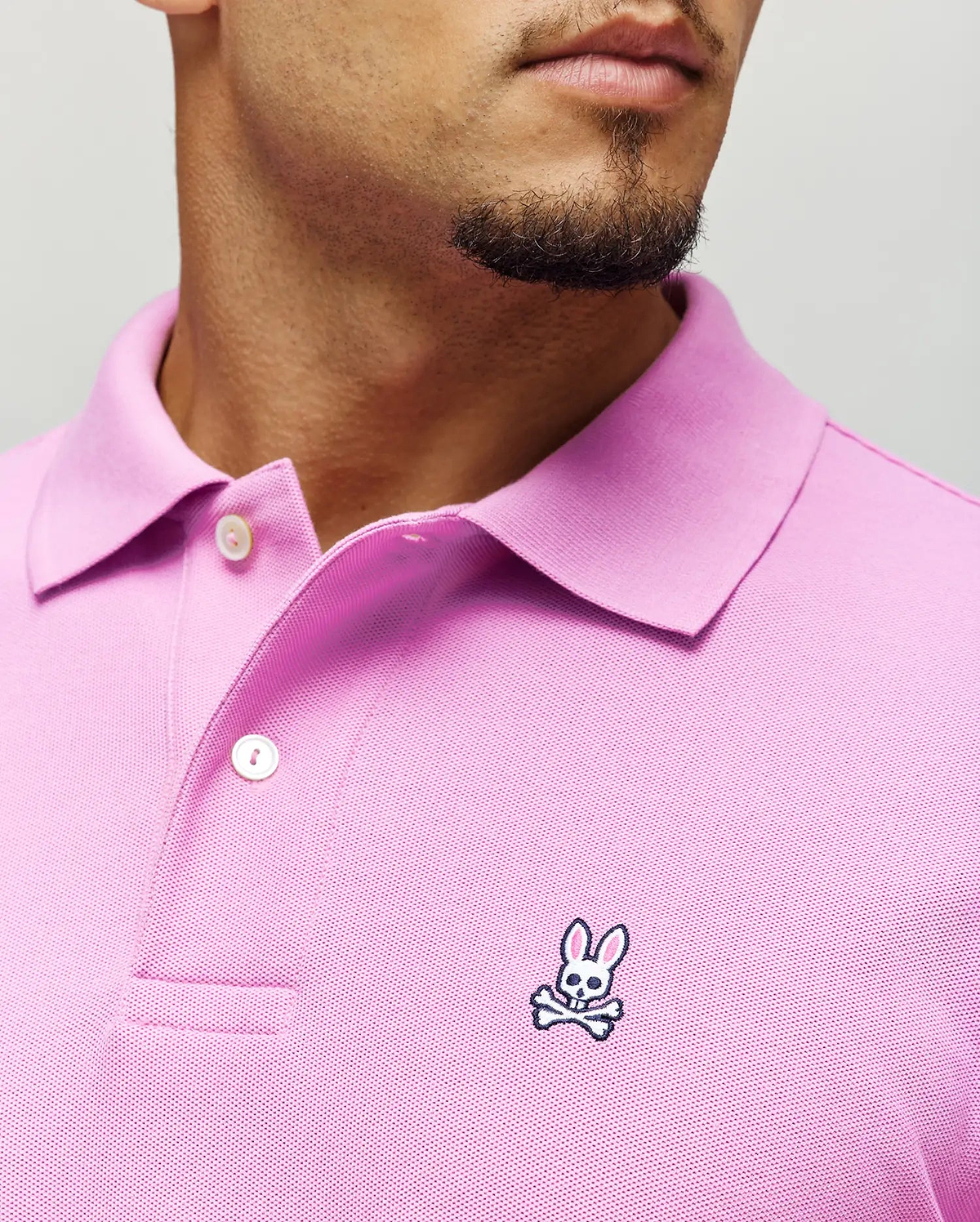Mens Classic Pique Polo in vibrant pink pique fabric, featuring a classic fit, two white buttons, and a small embroidered Psycho Bunny skull logo with pink ears on the left chest.