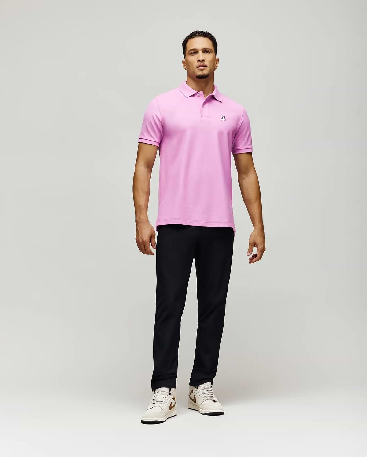 Mens Classic Pique Polo, a vibrant pink classic fit polo shirt crafted from textured pique fabric, featuring a small, intricately embroidered Psycho Bunny skull logo on the left chest.