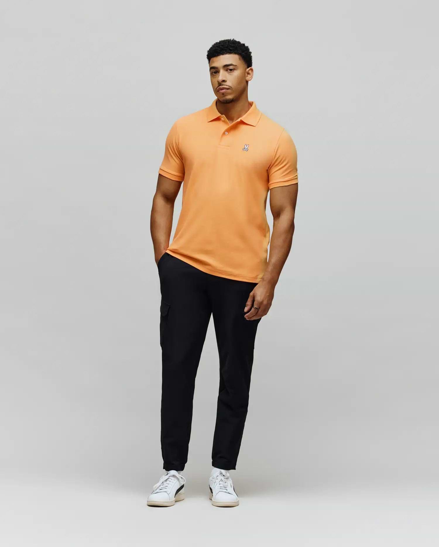 Mens Classic Pique Polo in apricot orange, featuring a classic fit and pique texture, with a small embroidered white Psycho Bunny skull logo on the left chest. (1)