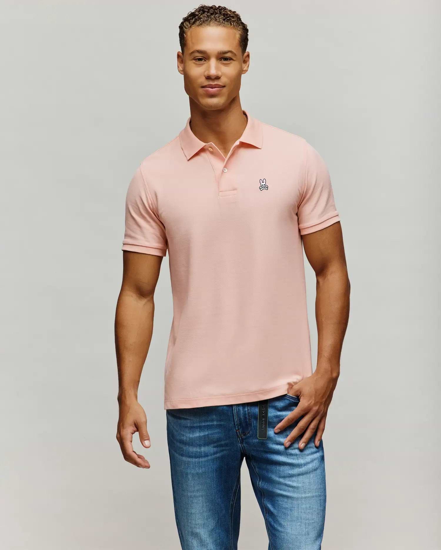 Mens Classic Pique Polo in light pink, featuring a classic fit, two-button placket, and a small embroidered white and black Psycho Bunny skull logo on the left chest.