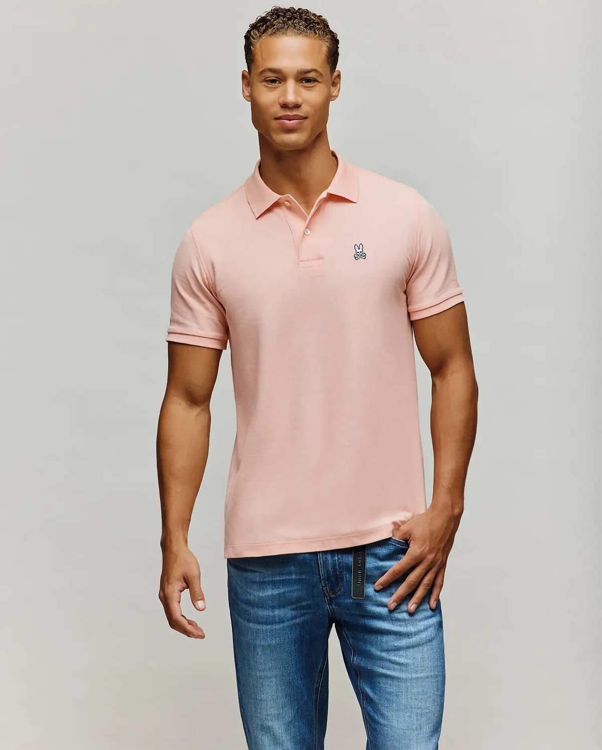 Mens Classic Pique Polo in light pink, featuring a classic fit, two-button placket, and a small embroidered white and black Psycho Bunny skull logo on the left chest.