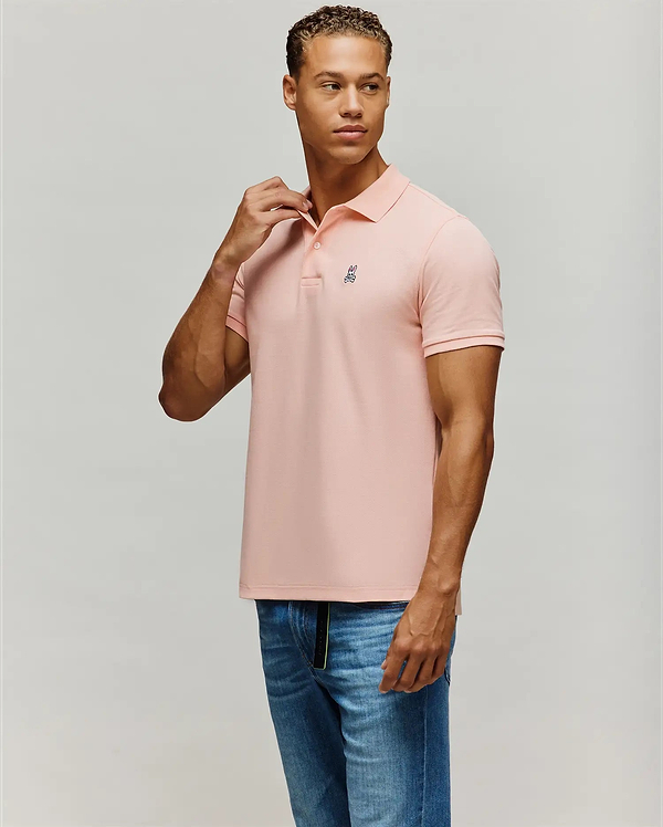 Mens Classic Pique Polo in light pink, featuring a classic fit, textured pique knit fabric, two-button placket, and a small embroidered Psycho Bunny skull logo on the left chest.