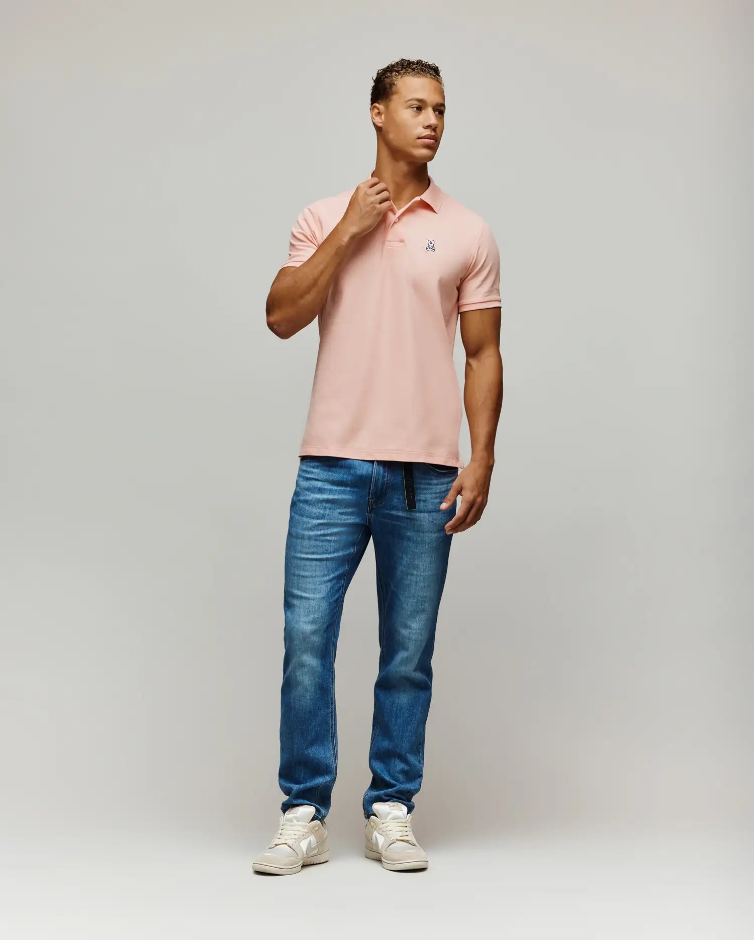 Mens Classic Pique Polo in soft peach, a classic fit shirt crafted from textured pique fabric, featuring a small, iconic embroidered Psycho Bunny skull logo on the left chest with white, black, and red details.