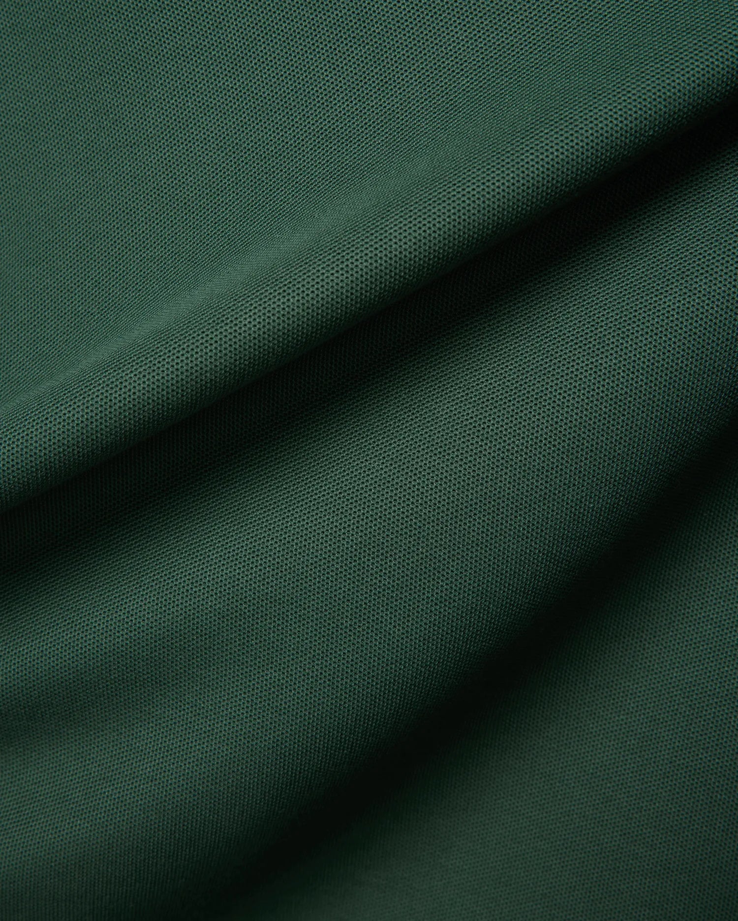 Mens Classic Pique Polo in a deep forest green, highlighting the refined, textured pique fabric with elegant folds, embodying Psycho Bunny's premium streetwear.