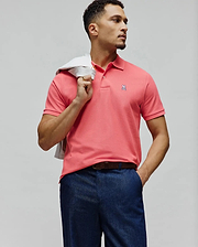 Mens Classic Pique Polo in vibrant coral pink, featuring a classic fit, two-button placket, and a small embroidered white Psycho Bunny skull logo with pink and black details on the left chest.