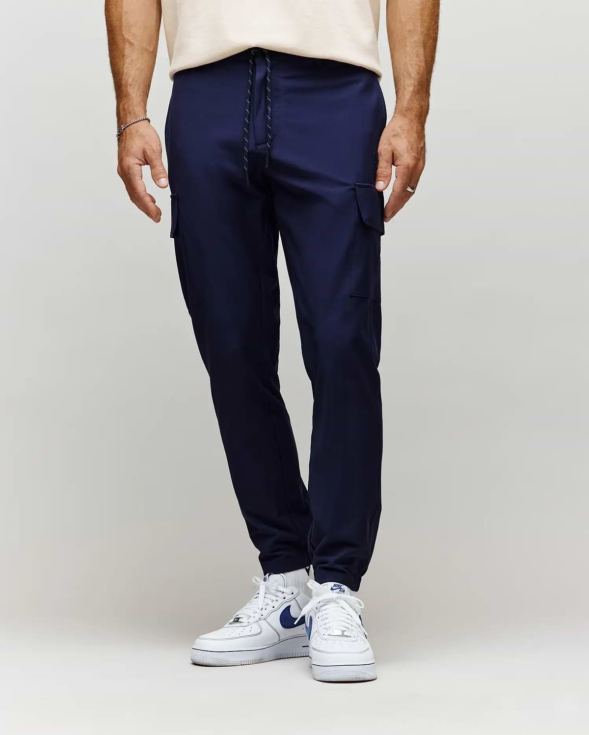 Mens Lloyd Cargo Jogger in navy blue, featuring a slim, tapered fit, smooth fabric, side cargo pockets, and a black and white drawstring waist with ribbed cuffs.