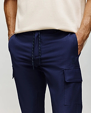 Mens Lloyd Cargo Jogger in navy blue, featuring a relaxed fit, smooth fabric, white speckled drawstring, side cargo pockets, and a small tonal embroidered Psycho Bunny skull logo on the left thigh.