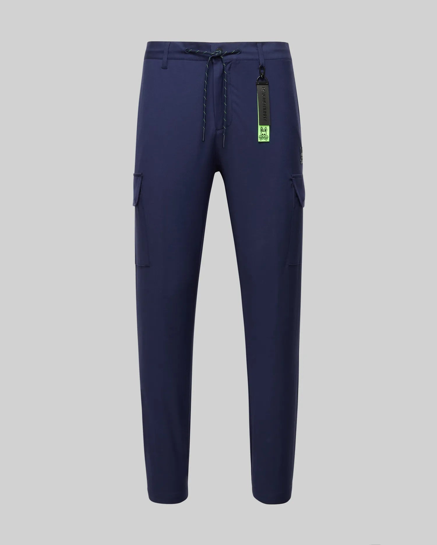 Mens Lloyd Cargo Jogger in navy blue, featuring a relaxed fit, smooth fabric, side cargo pockets, a lime green drawstring, and a prominent Psycho Bunny logo keychain with a small embroidered bunny skull on the pocket.