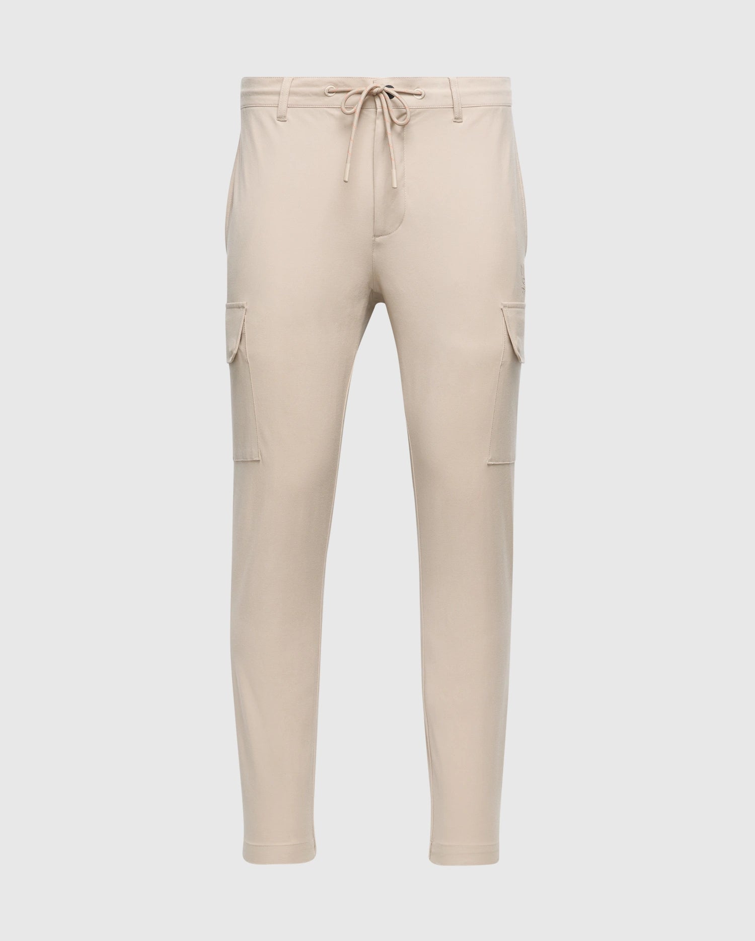 The MENS LLOYD CARGO JOGGER - B6P159B200 by Psycho Bunny is a pair of slim-fit beige cargo jogger pants, featuring tapered legs, an elastic waistband with a drawstring, two side pockets, and two cargo pockets on the thighs. These joggers are adorned with a subtle silicone branded detail.