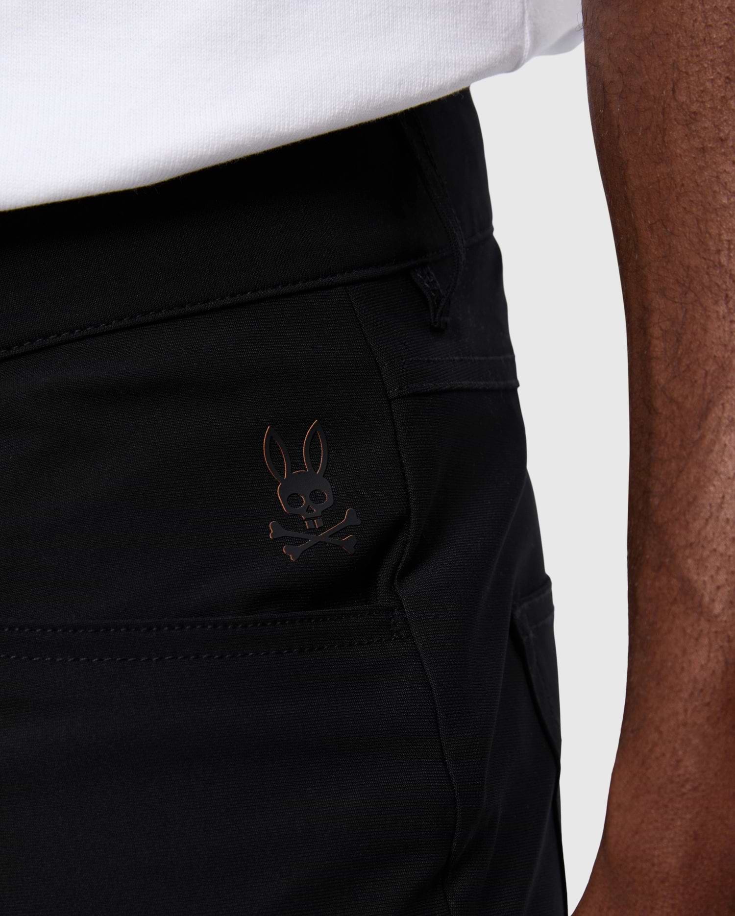 Mens Maverick 10k Step Pant 31 1/2 L in black smooth woven fabric, featuring a small metallic bronze embroidered Psycho Bunny skull logo on the upper left thigh.