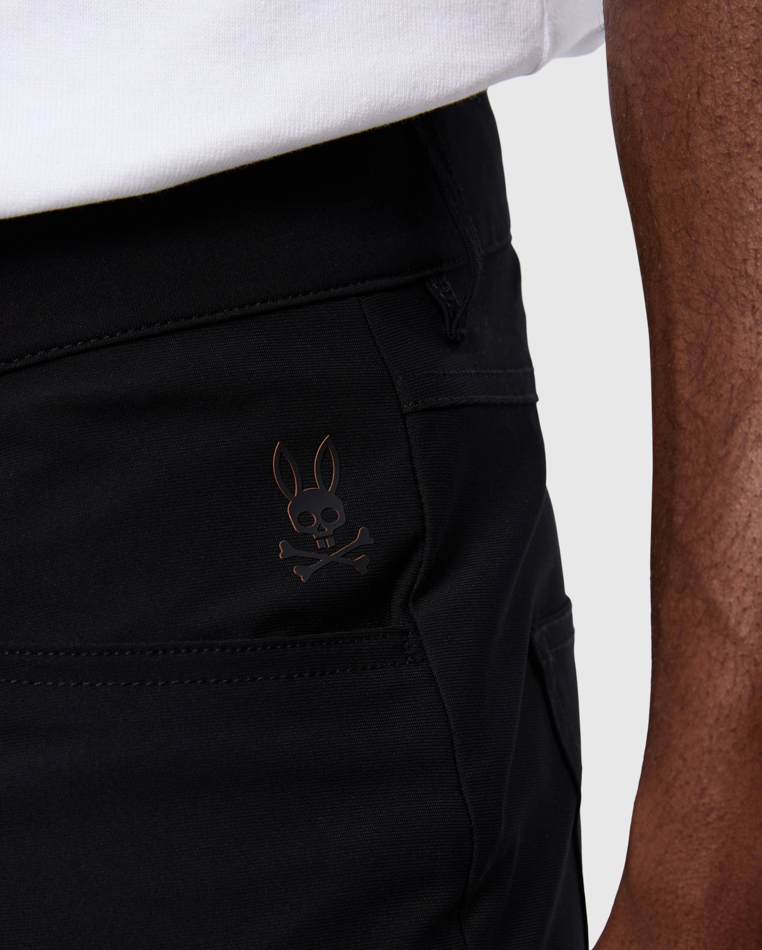Mens Maverick 10k Step Pant 31 1/2 L in black smooth woven fabric, featuring a small metallic bronze embroidered Psycho Bunny skull logo on the upper left thigh.