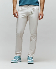 Mens Maverick 10k Step Pant, light beige, slim fit, smooth premium fabric, with a small embroidered green Psycho Bunny skull logo on the right front pocket.