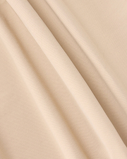 A close-up of beige fabric with a smooth texture and gentle folds creating soft shadows. The material appears lightweight with a plain weave, ideal for crafting the versatile MENS 10K STEP PANT - B6P788D200 by Psycho Bunny, featuring its stylish five-pocket design.