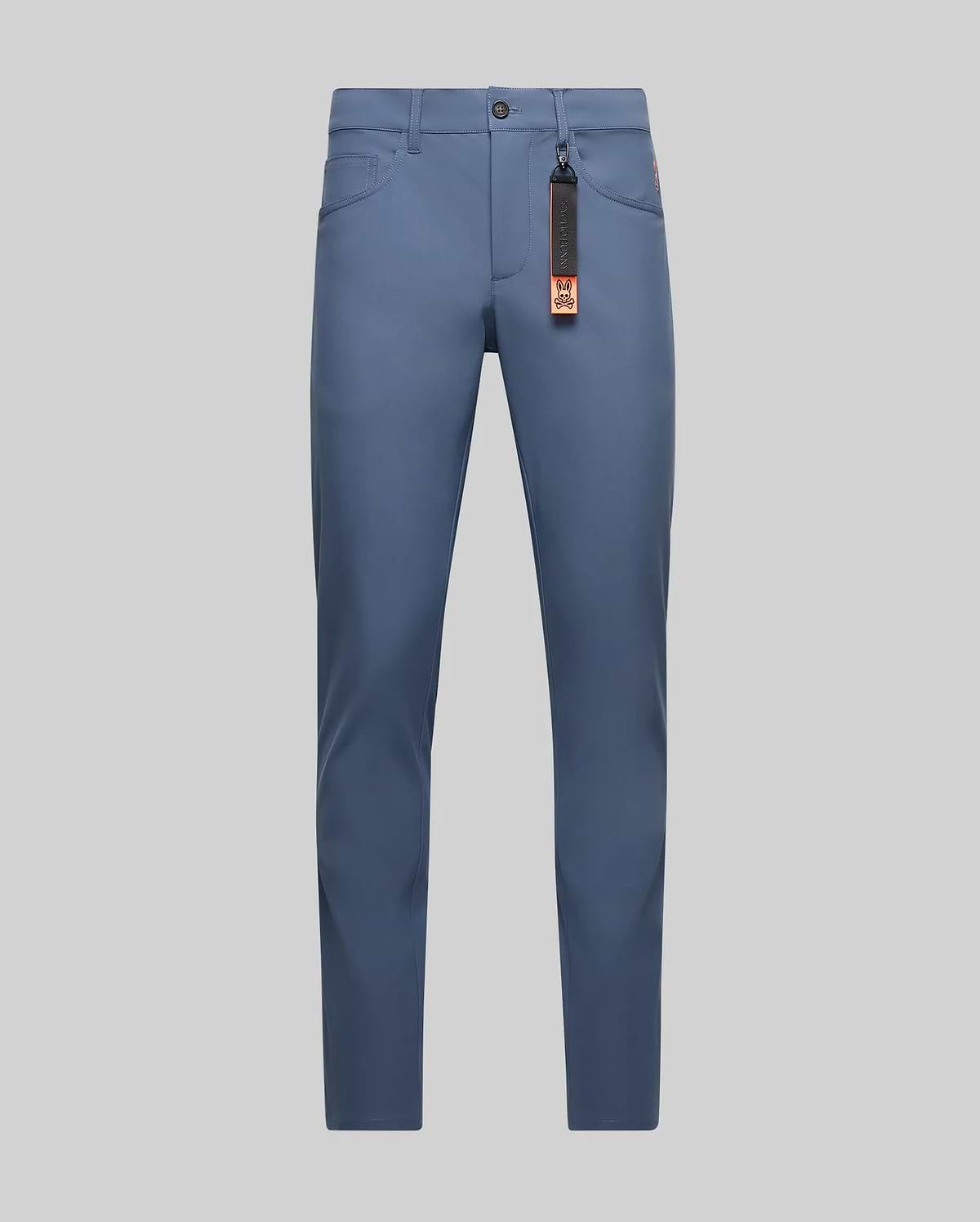 Dusty blue Mens Maverick 10k Step Pant, slim fit, smooth performance fabric, with a small embroidered orange Psycho Bunny skull logo on the right hip and a black and orange branded keychain.