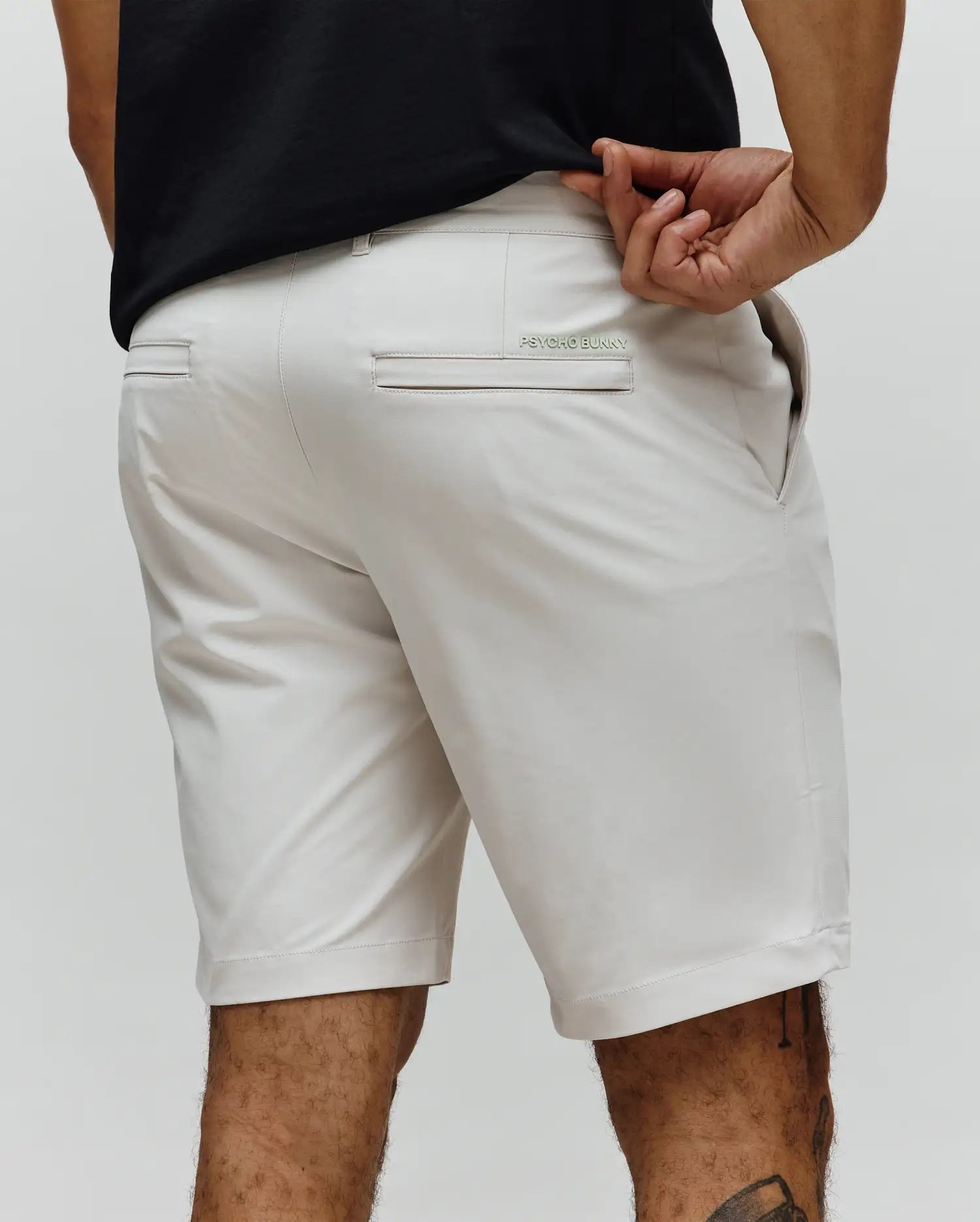 Mens Maverick 10k Step Short in stone, featuring a classic fit and smooth performance fabric. Small mint green embroidered Psycho Bunny text logo on the back right welt pocket.