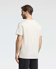 A man with brown hair, facing away from the camera against a plain background, wears a Psycho Bunny MENS CLASSIC CREW NECK TEE - B6U014B200 in vibrant colors, paired with black pants.
