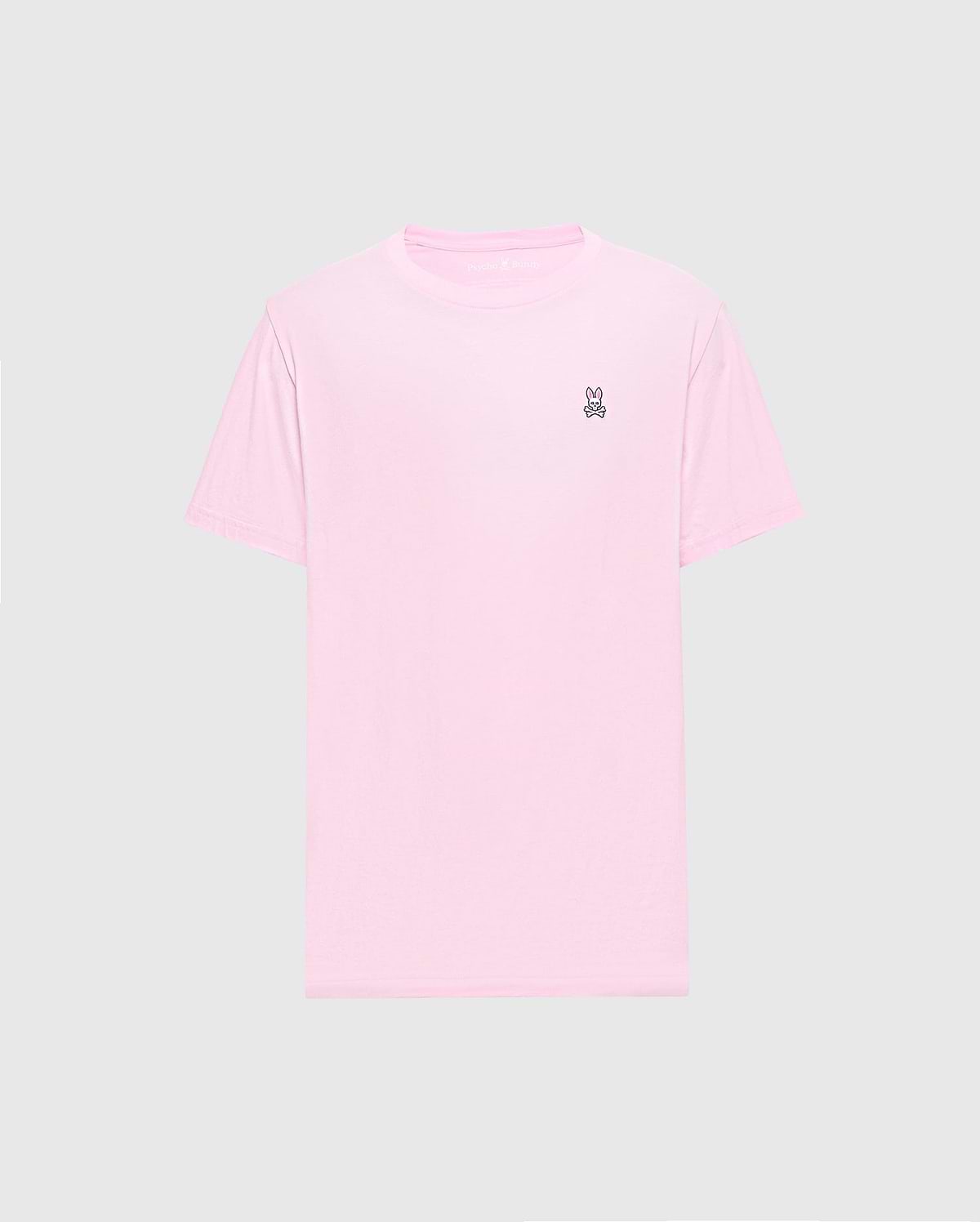 The light pink Men's Classic Crew Neck Tee (B6U014CRPC) by Psycho Bunny is crafted from soft pima cotton with a small embroidered peace sign hand symbol on the top left chest against a plain gray background, making it versatile and stylish for any casual occasion.