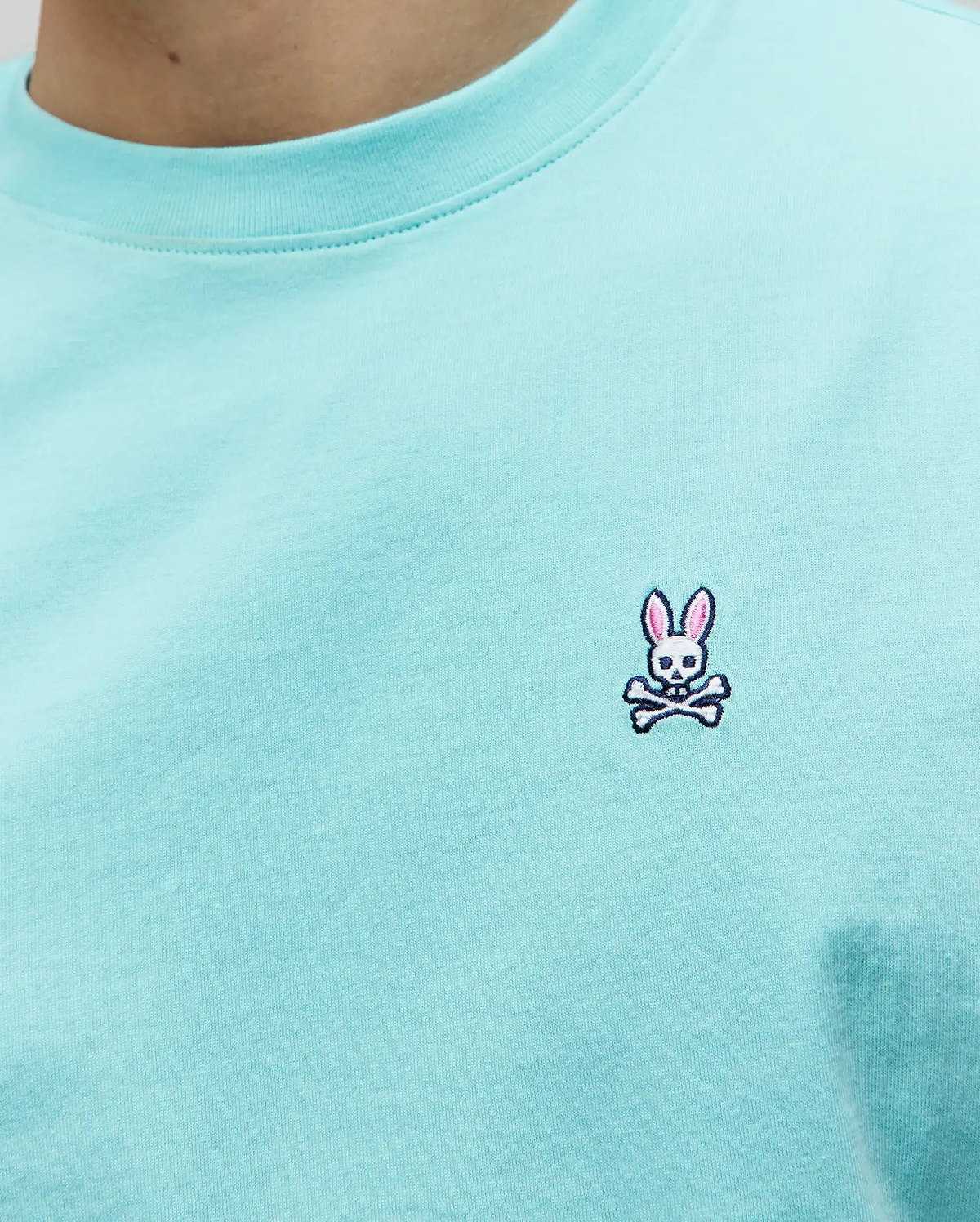 Mens Classic Crew Neck Tee in vibrant aqua jersey knit, showcasing the iconic small embroidered Psycho Bunny skull logo with pink ears, white skull, and black crossbones on the left chest, embodying refined streetwear.