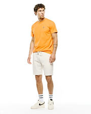 Mens Classic Crew Neck Tee in vibrant orange, crafted from smooth jersey fabric with a classic fit, featuring a small embroidered Psycho Bunny skull logo on the left chest. Cream french terry shorts complete the look.