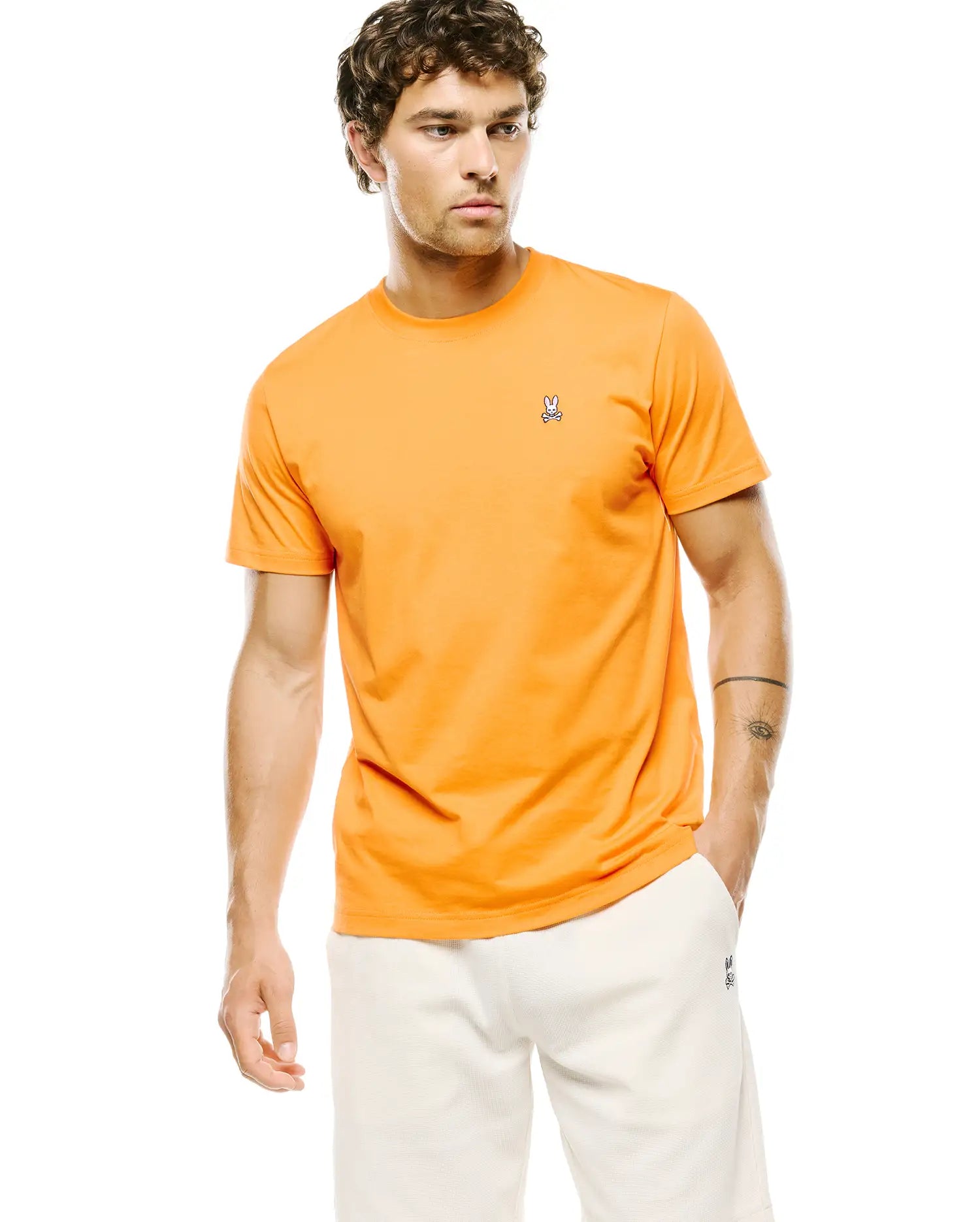 Mens Classic Crew Neck Tee in vibrant orange jersey knit, featuring a classic fit and a small, embroidered Psycho Bunny skull logo on the left chest.