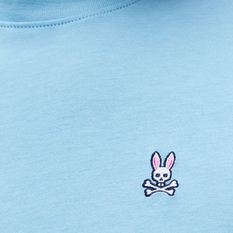 Mens Classic Crew Neck Tee in light blue jersey knit, featuring a small embroidered Psycho Bunny skull logo with pink ears on the left chest, classic fit.